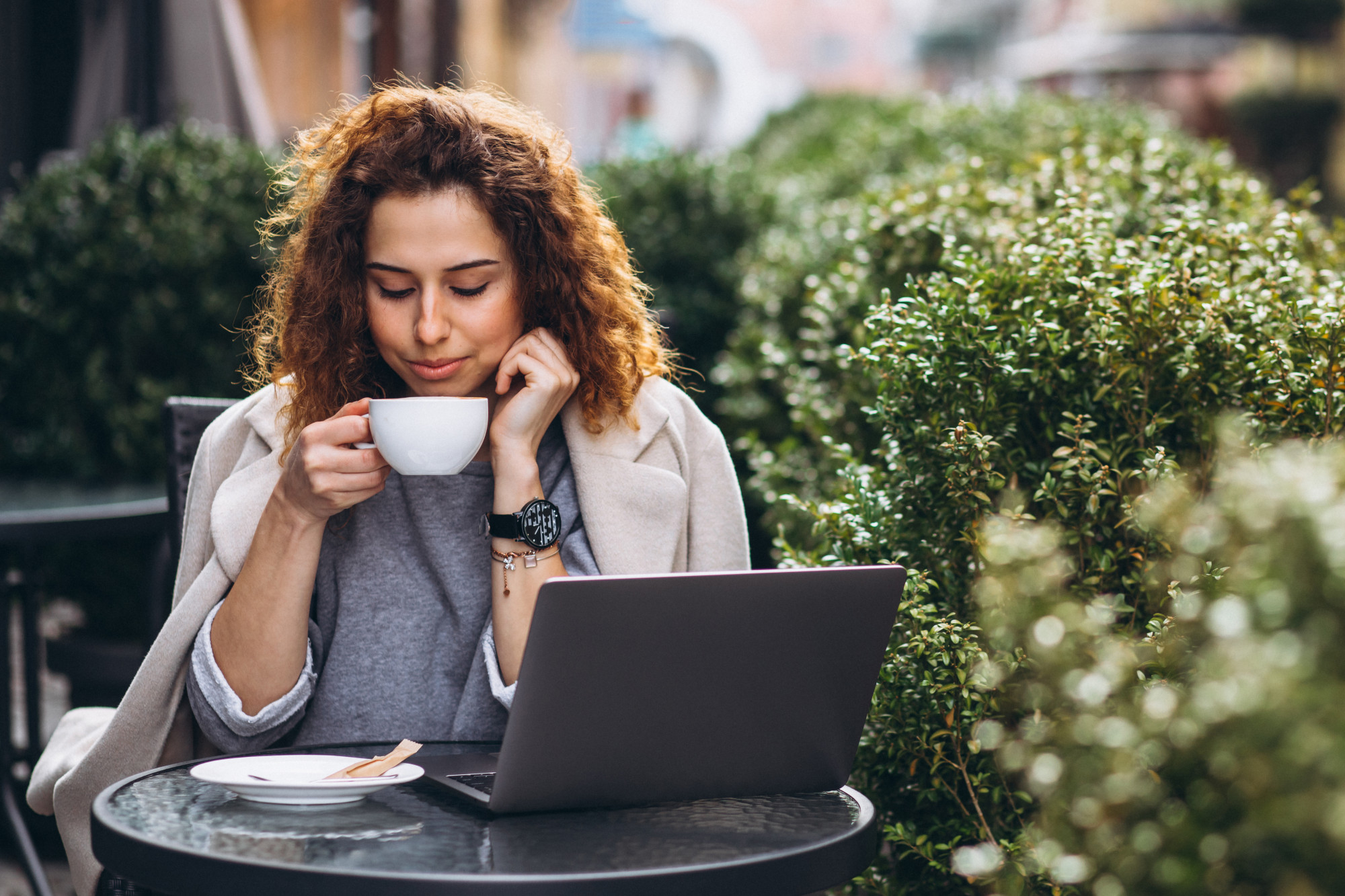 Woman sipping coffee while viewing her laptop